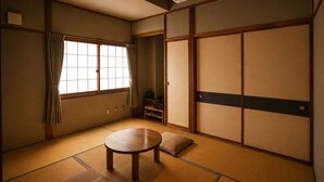 A traditional Japanese room with tatami flooring, sliding doors, and a small table.