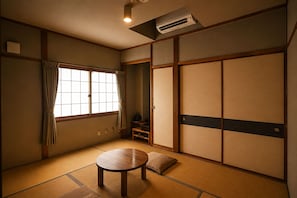 Une pièce de style japonais traditionnel, avec un sol recouvert de tatamis, des portes coulissantes et une petite table.