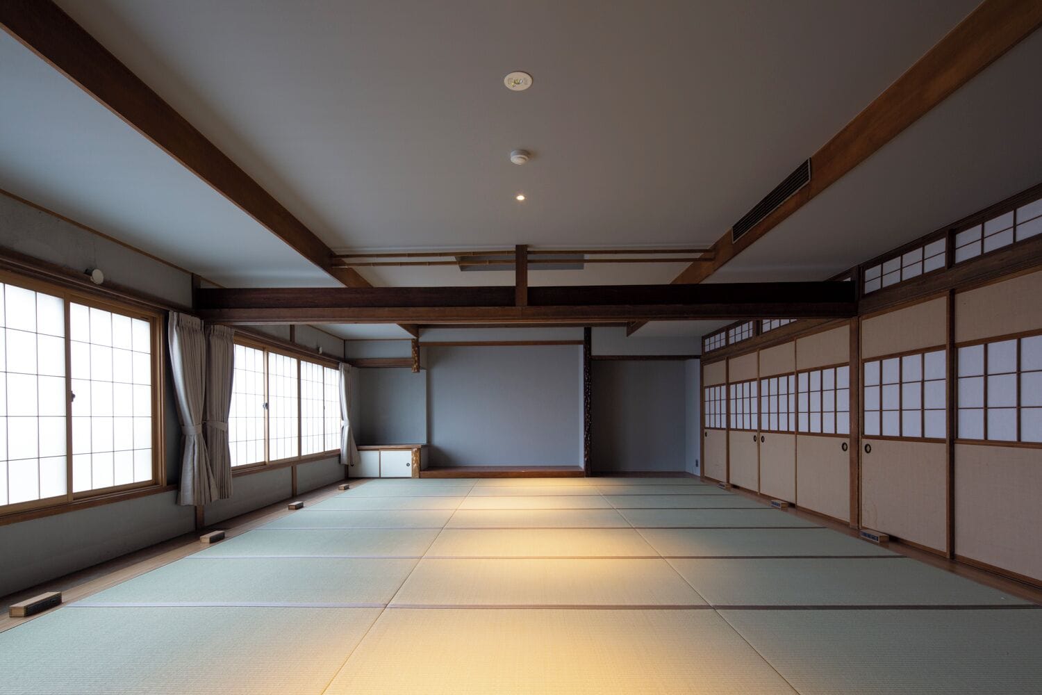 A traditional Japanese room with tatami flooring, sliding doors, and a low ceiling.