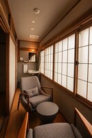 Un interior japonés tradicional con suelo de tatami, una mesa de madera baja y una zona de estar con una silla acolchada.