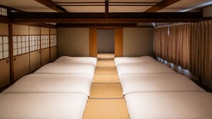 A traditional Japanese-style room with tatami flooring, sliding doors, and a central corridor leading to a door.