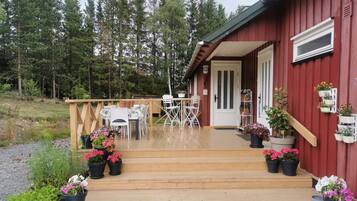 A wooden deck with outdoor furniture, a door, and potted plants.