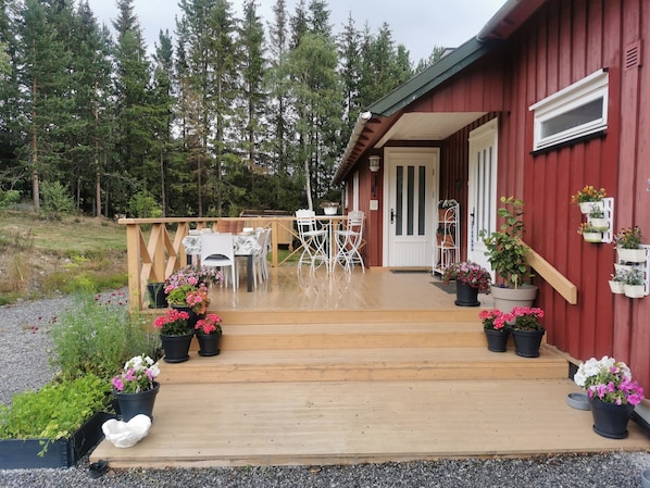 A wooden deck with outdoor furniture, a door, and potted plants.