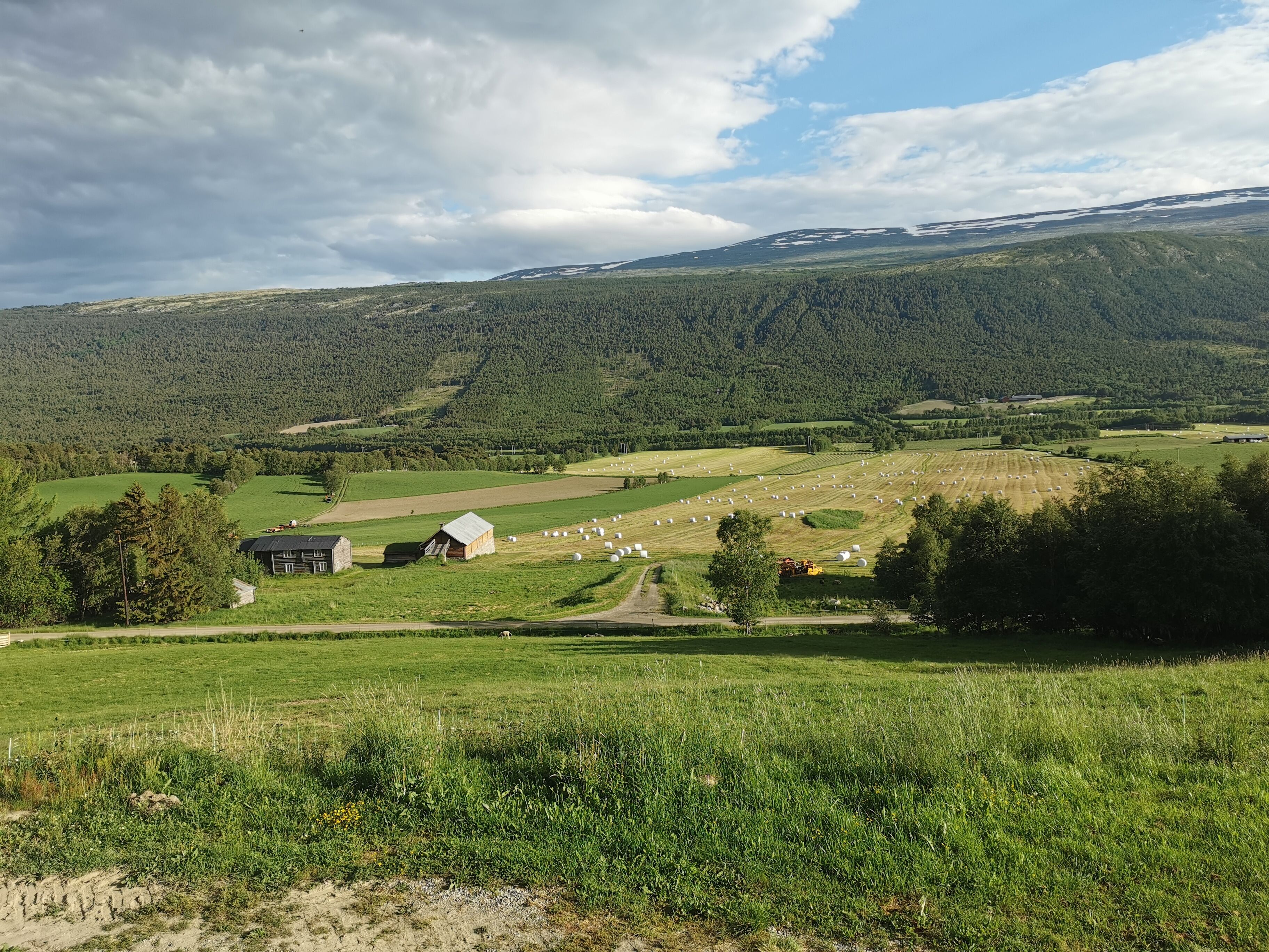 Paisaje rural con un granero, fardos de heno y un camino.