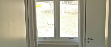 A room with a window, a door, and a view of the outdoors.