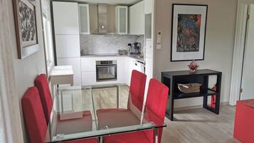 A modern kitchen with white cabinets, a built-in oven, and a coffee maker.