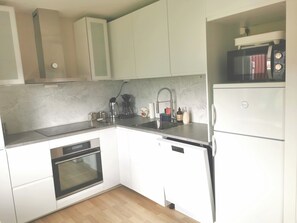A modern kitchen with white cabinetry, a built-in oven, a dishwasher, and a microwave.