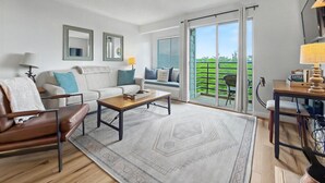 Een moderne woonkamer met een bank, salontafel en uitzicht op een balkon.