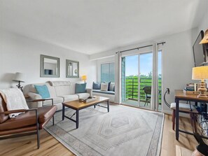Ein modernes Wohnzimmer mit einer Couch, einem Couchtisch und Blick auf einen Balkon.