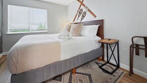 Een slaapkamer met een bed, nachtkastje en een raam met jaloezieën.