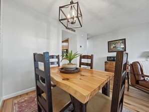 A dining area with a wooden table, chairs, a hanging light fixture, and a potted plant. - Cloudline Condo | Gatlinburg | Fireplace & Pools! (Gatlinburg)