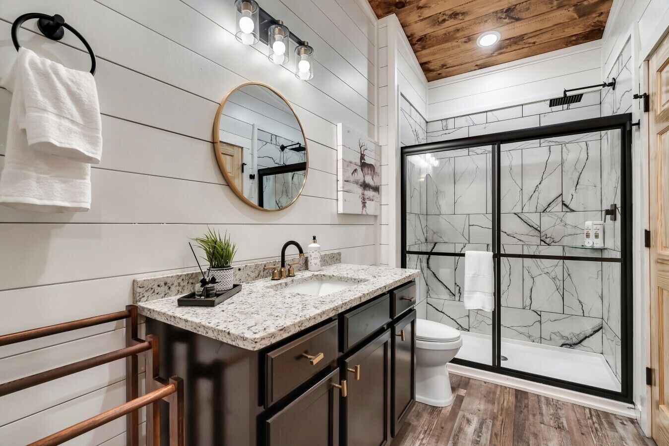 A modern bathroom with a marble shower enclosure, a freestanding bathtub, and a vanity with a granite countertop.