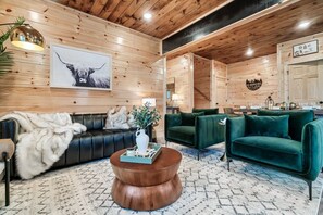 Ein gemütlicher Wohnbereich mit einem Ledersofa, grünen Sesseln und einem Couchtisch.