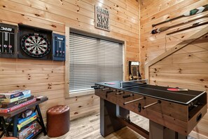 Ein Zimmer mit Tischfußball, Dartscheiben und einem Fenster mit Jalousien.