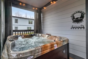 Ein Whirlpool mit Blick auf ein Haus, ein Schild mit Bär und Bäumen sowie das Logo von 'Pollywood Retreats'.