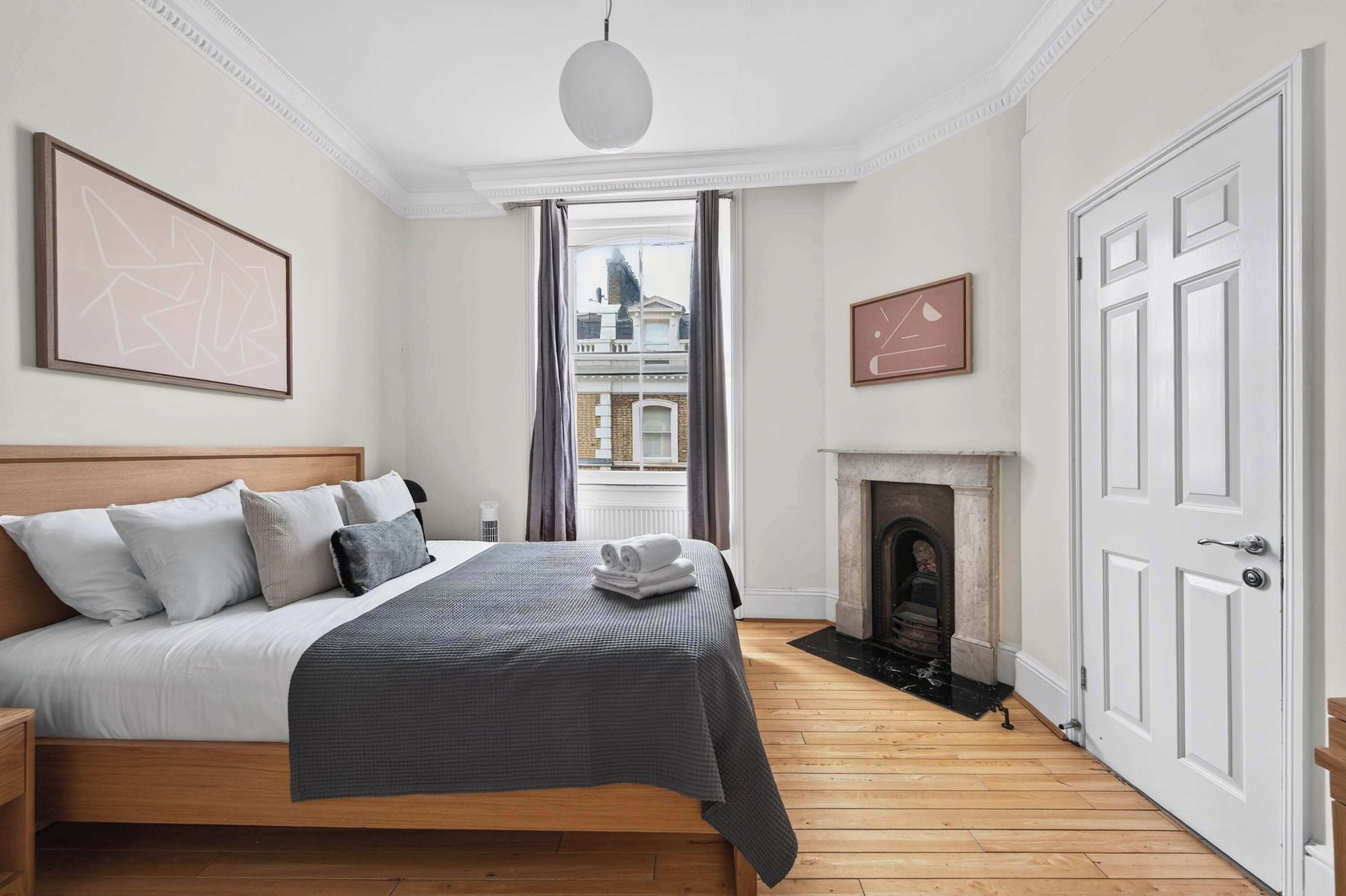 Une chambre d’hôtel avec un grand lit, une cheminée et une vue sur la ville par la fenêtre.