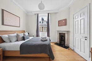Ein Hotelzimmer mit einem großen Bett, einem Kamin und Blick auf die Stadt durch das Fenster.