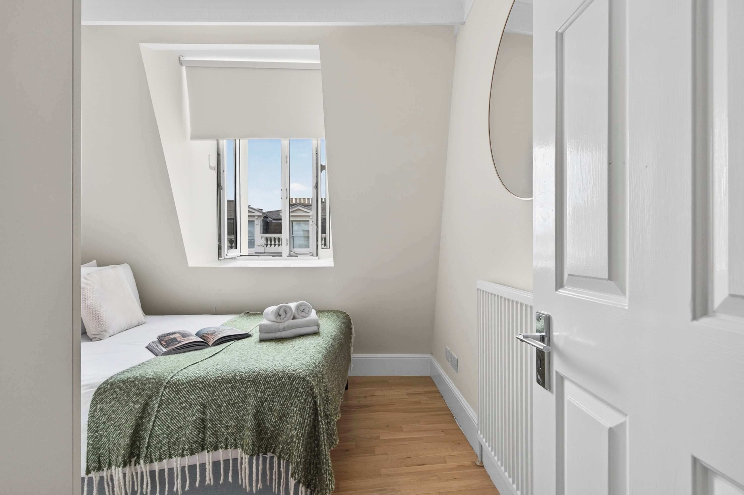 Une chambre à coucher avec un lit, une fenêtre, un radiateur et une porte.