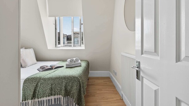 Ein Schlafzimmer mit einem Bett, einem Fenster, einer Heizung und einer Tür.