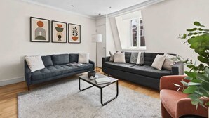 Ein modernes Wohnzimmer mit zwei Sofas, einem Couchtisch und gerahmten Kunstwerken an der Wand.
