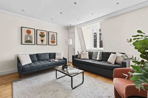 Ein modernes Wohnzimmer mit zwei Sofas, einem Couchtisch und gerahmten Kunstwerken an der Wand.