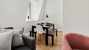 Ein modernes Wohnzimmer mit Essbereich, einer Couch, einem Sessel und einem für eine Mahlzeit gedeckten Tisch.