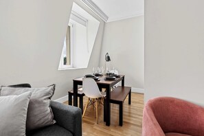 Ein modernes Wohnzimmer mit Essbereich, einer Couch, einem Sessel und einem für eine Mahlzeit gedeckten Tisch.