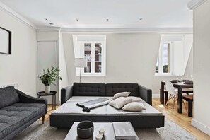 A modern living room with a sofa, a coffee table, and a dining area with a table and chairs. - South Ken 2-Bed - Science Museum - Lift - Sleeps 6 (London)