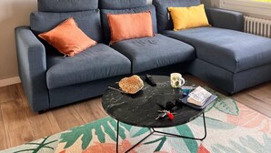 En moderne stue med en modulsofa, et sofabord og et dekorativt spejl på væggen.