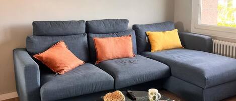A modern living room with a sectional sofa, a coffee table, and a decorative mirror on the wall.