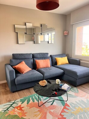 Ein modernes Wohnzimmer mit einem Ecksofa, einem Couchtisch und einem dekorativen Spiegel an der Wand.