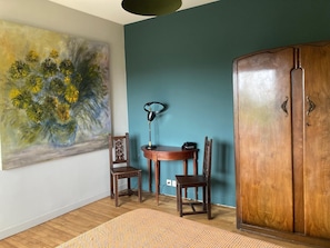 Ein Zimmer mit Holzboden, einem Tisch mit Stühlen, einem Bild an der Wand und einem Holzschrank.