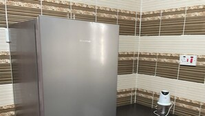 Una cocina con refrigerador de acero inoxidable, encimera negra y salpicadero de azulejos.