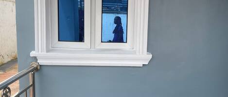 Una escalera con barandilla de metal y una ventana con marco blanco.