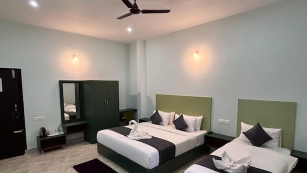 Una habitación de hotel con dos camas, un ventilador de techo, un espejo y una mesita de noche.