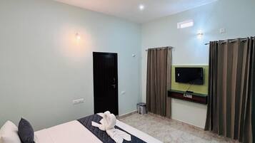 A hotel room with a bed, a ceiling fan, a TV, and curtains.