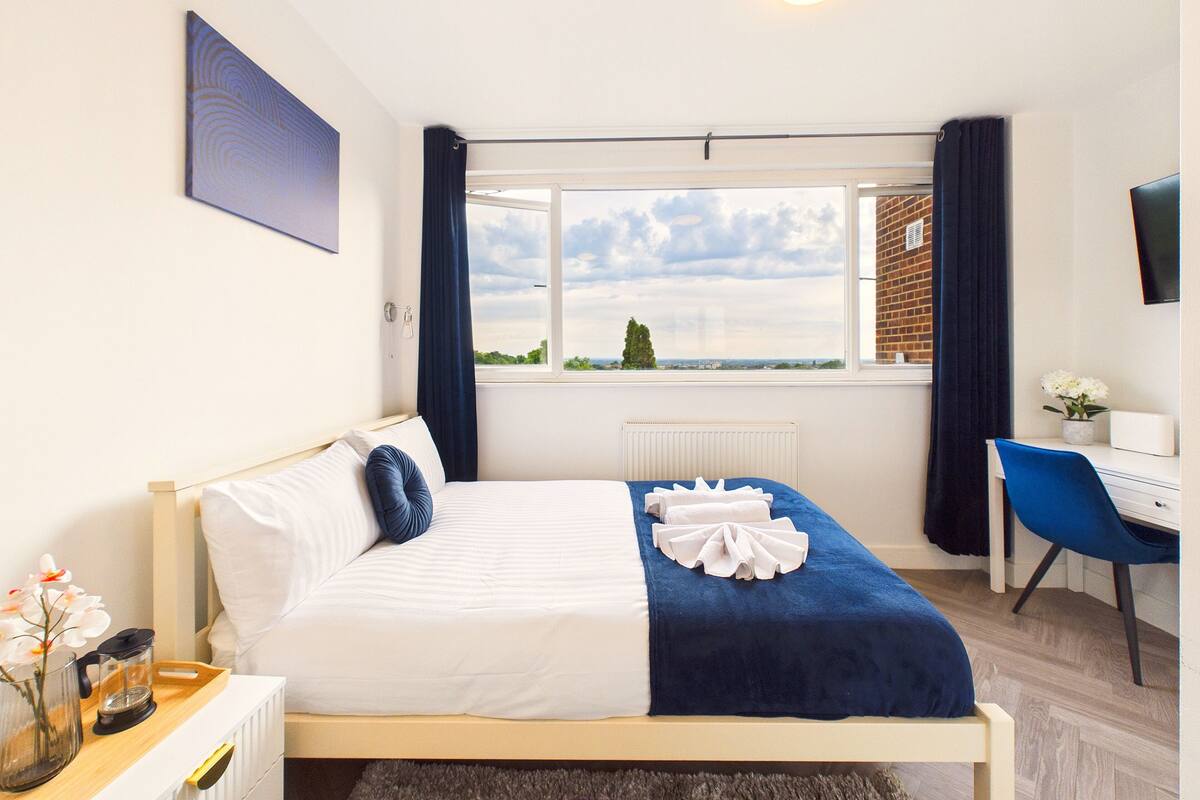 Un dormitorio con cama, escritorio, silla, ventana con vistas y radiador.