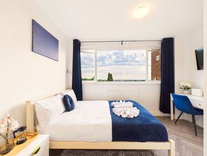 Un dormitorio con cama, escritorio, silla, ventana con vistas y radiador.
