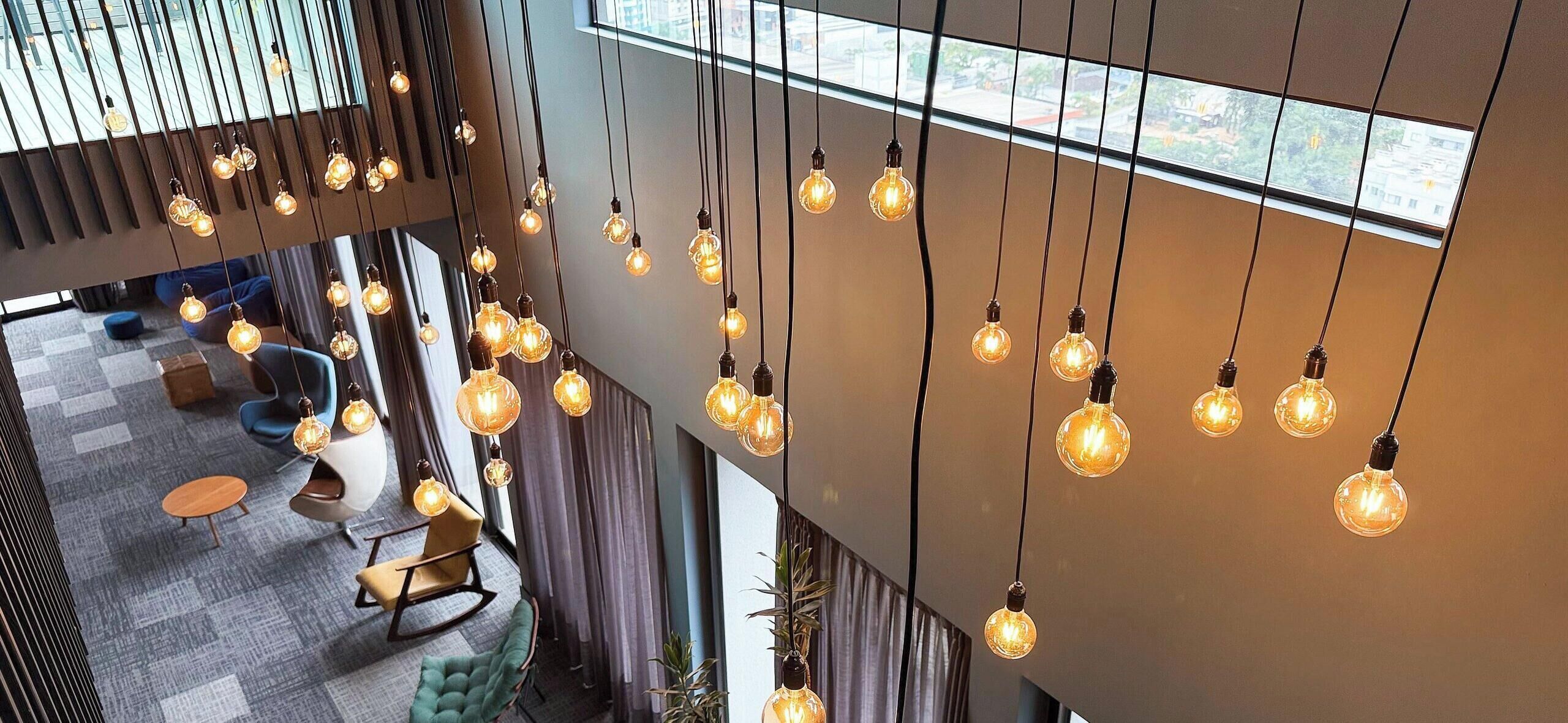 Een modern interieur met hanglampen, een zithoek met een bank en stoelen, en uitzicht door een raam.