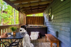 A covered outdoor area with a table, chairs, a bench, and a hot tub.