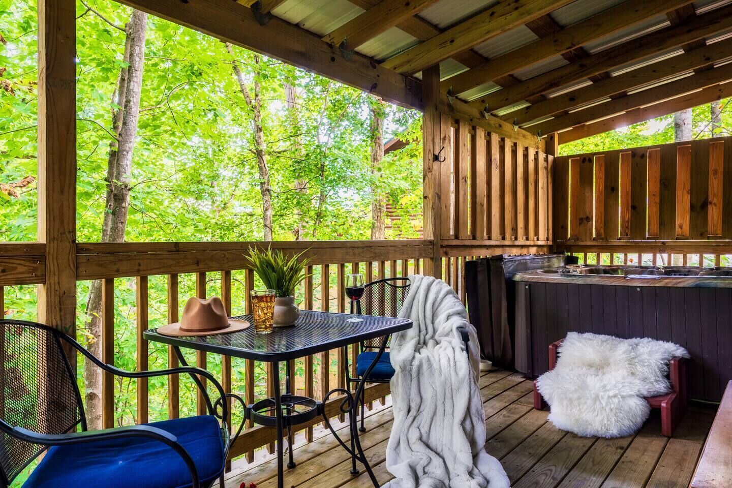 An outdoor deck with a table, chairs, a hot tub, and a wooden fence.