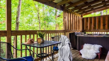 An outdoor deck with a table, chairs, a hot tub, and a wooden fence.