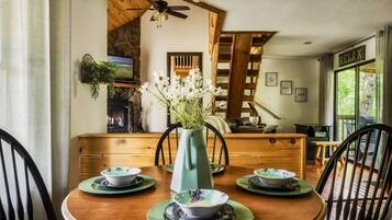 A dining area with a wooden table, chairs, and a vase of flowers.