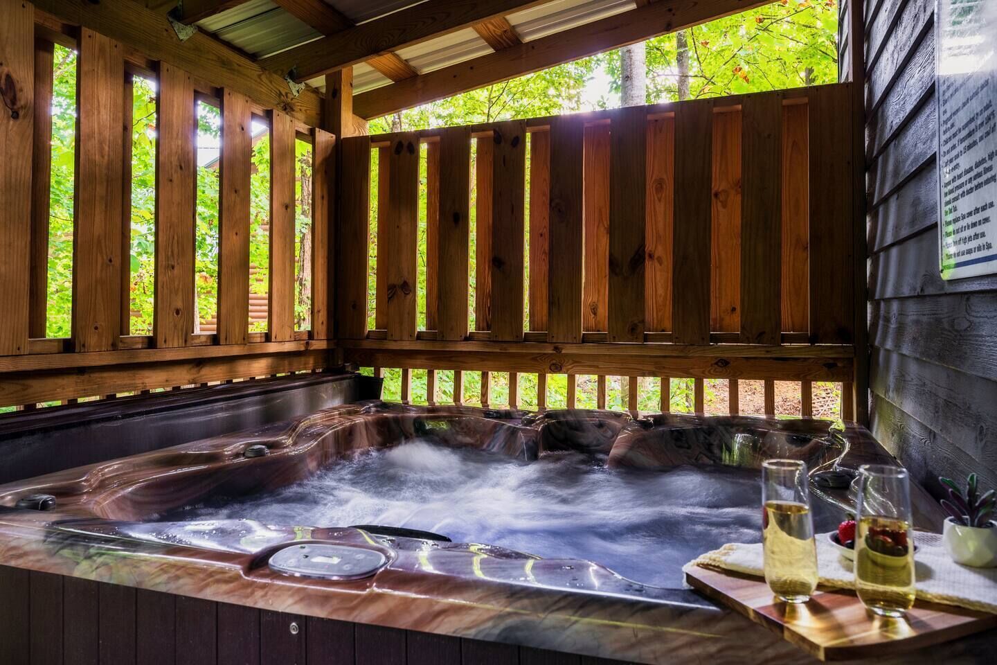 A hot tub with a wooden deck and a view of trees.