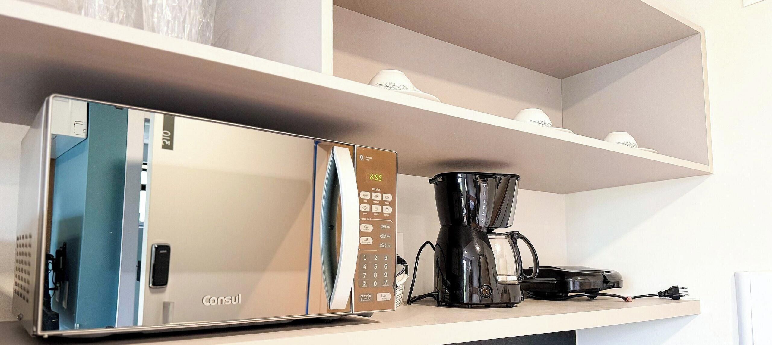 A kitchenette with a refrigerator, coffee maker, and a microwave.