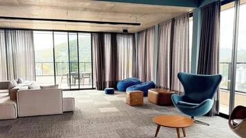 Una sala de estar moderna con un sofá, sillones y vistas a un paisaje urbano a través de amplios ventanales.