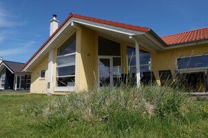 A yellow building with large windows and a red roof.