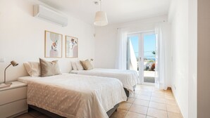 Habitación de hotel con dos camas, una mesita de noche, una lámpara y un ventilador de techo.