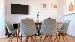 A dining area with a TV mounted on the wall, a table with chairs, and artwork on the wall. - CASA VISTA MAR - Lagos / Algarve - A stunning vacation home for up to 6 people (Lagos)