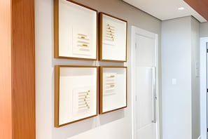 Ein Flur mit vier gerahmten Kunstwerken an der Wand, einer weißen Tür und einem weißen Schrank.